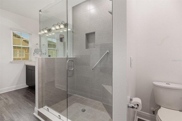 full bathroom featuring vanity, wood finished floors, a shower stall, baseboards, and toilet