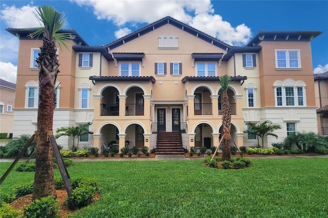 mediterranean / spanish home featuring a tiled roof, a front lawn, and stucco siding