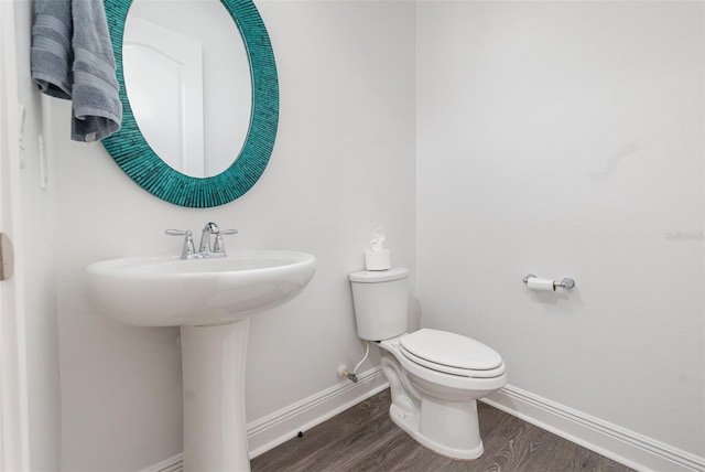 half bathroom with a sink, wood finished floors, toilet, and baseboards