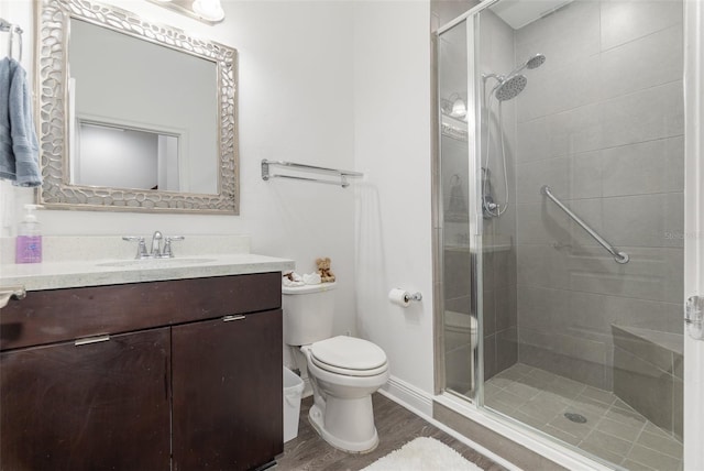 full bath with a stall shower, vanity, toilet, and wood finished floors