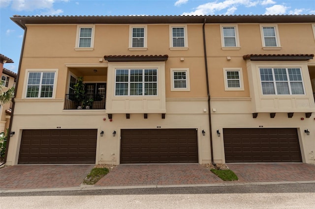 view of property featuring driveway, an attached garage, and stucco siding