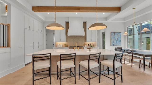 kitchen featuring white cabinetry, light countertops, premium range hood, beam ceiling, and backsplash