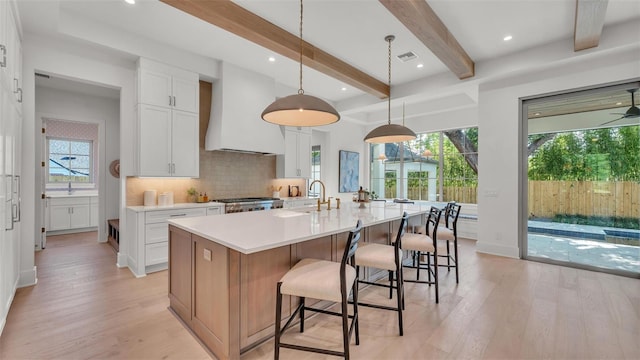 kitchen with custom exhaust hood, light wood-type flooring, and plenty of natural light