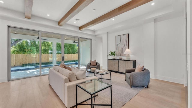 living room featuring recessed lighting, beamed ceiling, light wood-style flooring, and plenty of natural light