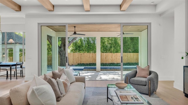 living room with beam ceiling, wood finished floors, a ceiling fan, and baseboards