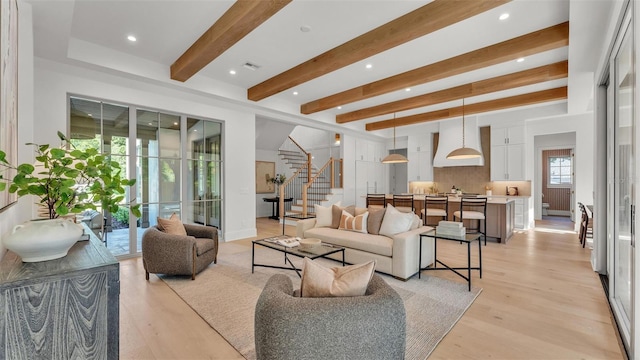 living room featuring stairway, recessed lighting, light wood finished floors, and beamed ceiling