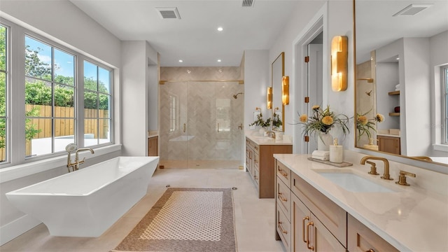 full bath featuring a stall shower, a sink, a freestanding tub, and visible vents