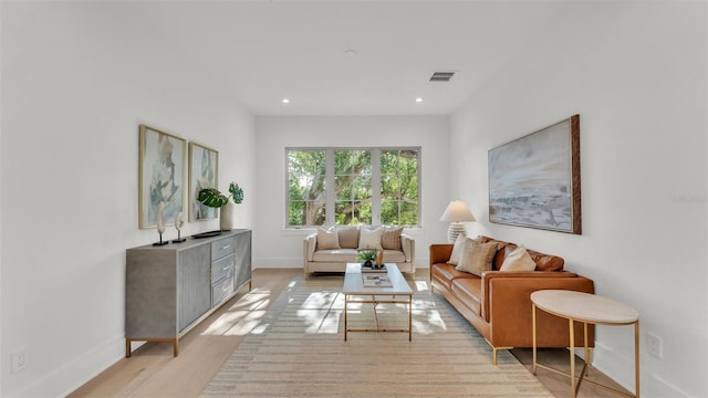 living area with baseboards, visible vents, light wood finished floors, and recessed lighting