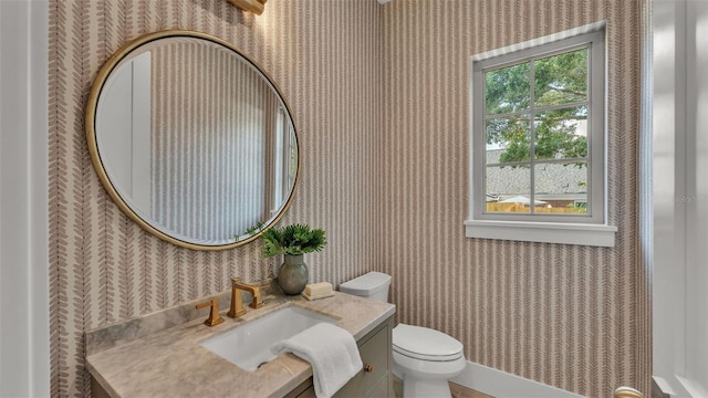 bathroom with wallpapered walls, toilet, and vanity