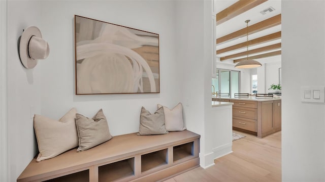 interior space with visible vents, light wood-style flooring, and beam ceiling