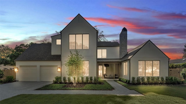 view of front of home featuring driveway, a standing seam roof, a front yard, an attached garage, and stucco siding