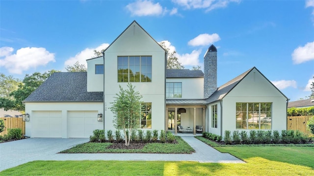 view of front of property featuring a front lawn, an attached garage, driveway, stucco siding, and fence