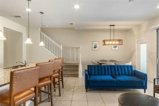 tiled living room with sink and a textured ceiling