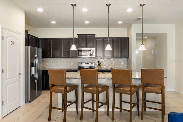 kitchen with stainless steel appliances, decorative light fixtures, a center island, and tasteful backsplash