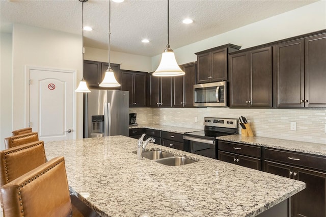 kitchen with backsplash, sink, decorative light fixtures, appliances with stainless steel finishes, and a breakfast bar area