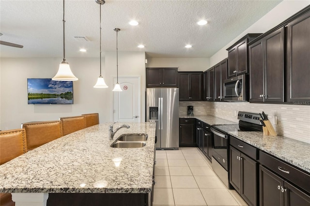 kitchen with backsplash, stainless steel appliances, sink, an island with sink, and hanging light fixtures