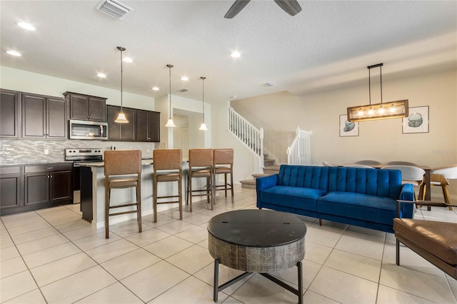 living room featuring ceiling fan, a textured ceiling, and light tile patterned flooring