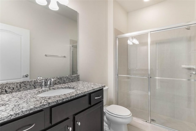 bathroom with a shower with shower door, vanity, and toilet