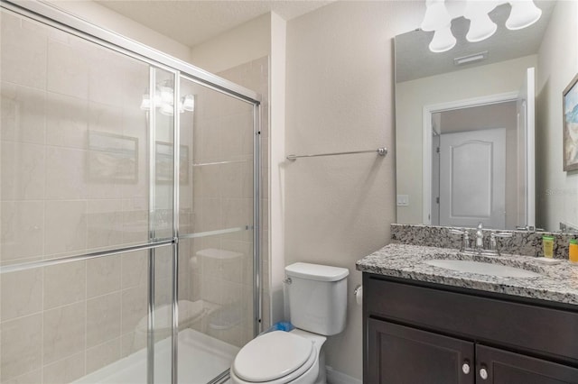 bathroom featuring a textured ceiling, an enclosed shower, toilet, and vanity