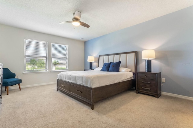 bedroom with ceiling fan, light carpet, and a textured ceiling