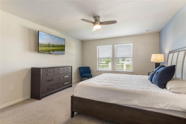 bedroom featuring light carpet, a ceiling fan, baseboards, and a textured ceiling