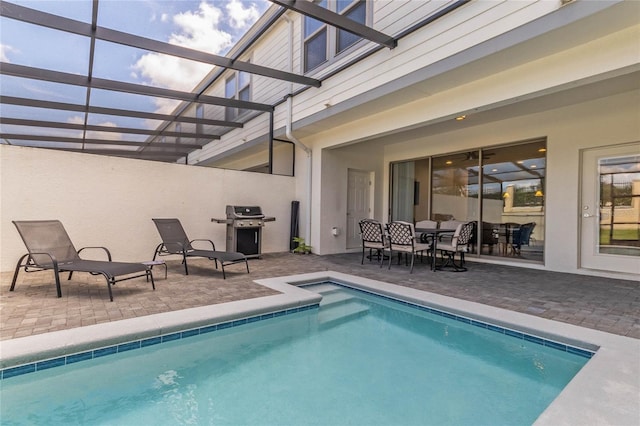 view of swimming pool featuring a lanai, a grill, and a patio