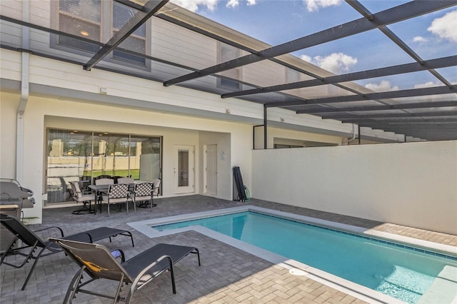 outdoor pool featuring glass enclosure, outdoor dining space, and a patio