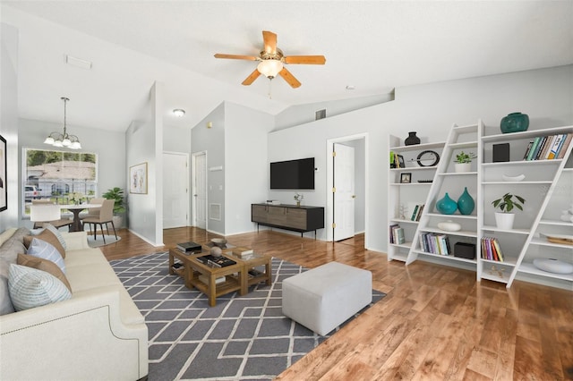 living room featuring ceiling fan with notable chandelier, dark wood-type flooring, and lofted ceiling