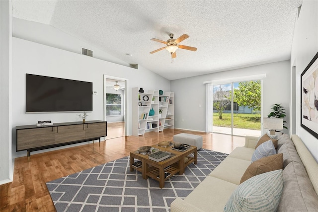 living room featuring lofted ceiling, ceiling fan, dark wood-type flooring, and a textured ceiling