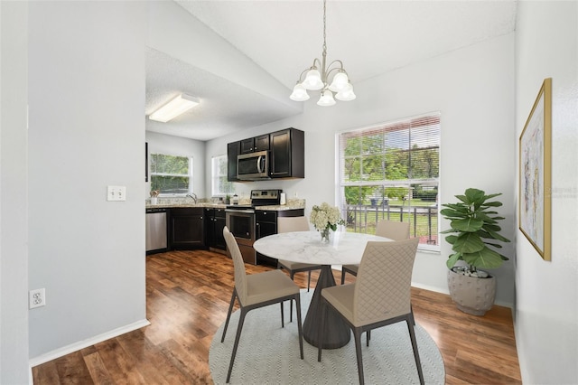 dining space featuring dark wood-type flooring, lofted ceiling, a wealth of natural light, and a chandelier