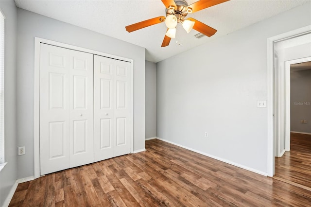 unfurnished bedroom with a textured ceiling, wood-type flooring, ceiling fan, and a closet