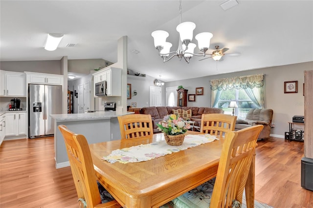 dining room with lofted ceiling, ceiling fan with notable chandelier, and light hardwood / wood-style floors