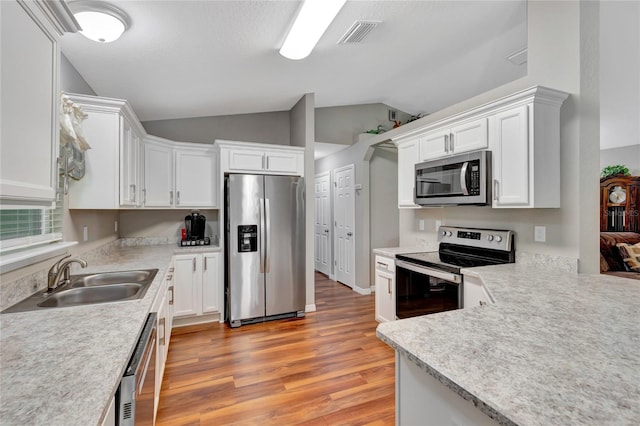 kitchen featuring light hardwood / wood-style flooring, appliances with stainless steel finishes, sink, white cabinetry, and lofted ceiling