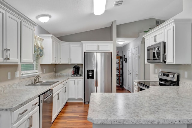 kitchen featuring stainless steel appliances, sink, vaulted ceiling, and white cabinets