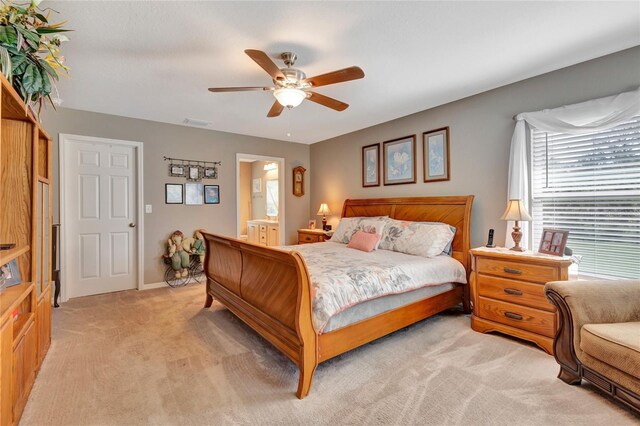 bedroom featuring light colored carpet, ceiling fan, and ensuite bathroom