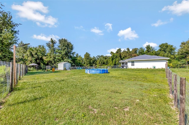 view of yard featuring a fenced in pool and a storage shed