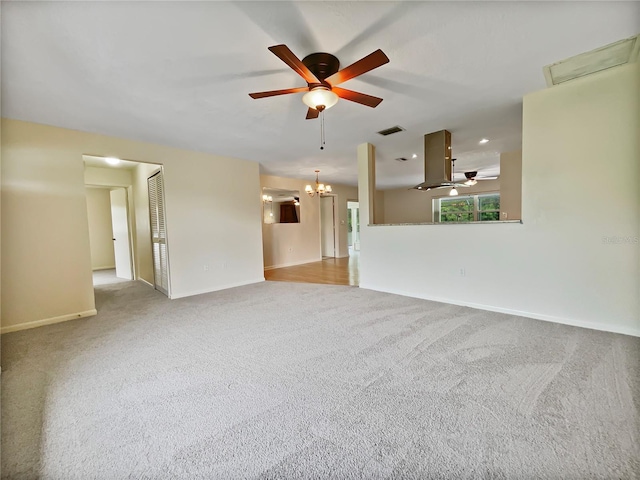 carpeted spare room with ceiling fan with notable chandelier