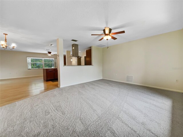 unfurnished living room with ceiling fan with notable chandelier, visible vents, and baseboards