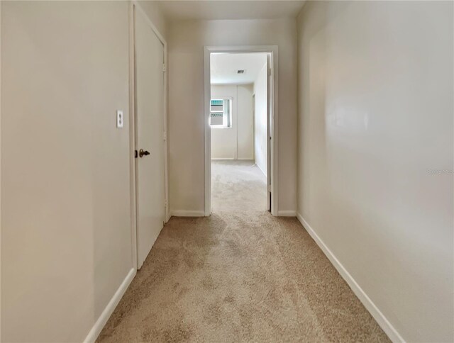 corridor with light carpet and baseboards