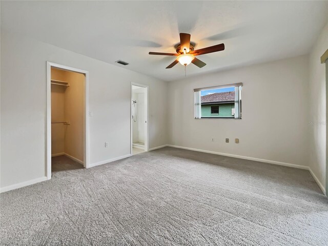 unfurnished bedroom with visible vents, baseboards, a closet, carpet, and a walk in closet