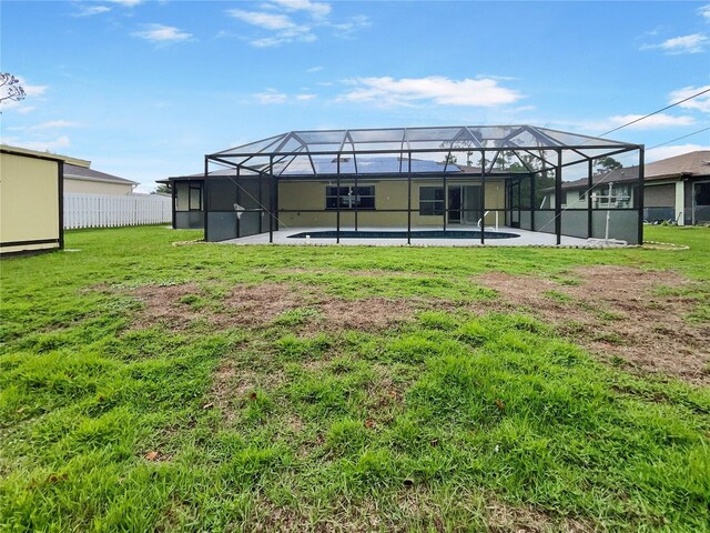 back of property with an outdoor pool, glass enclosure, a yard, and fence