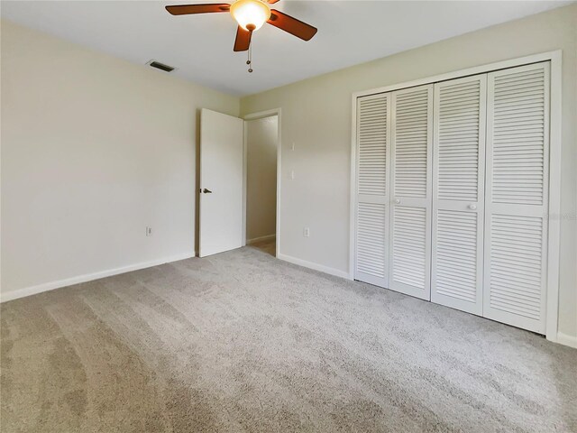 unfurnished bedroom featuring carpet flooring, a ceiling fan, visible vents, baseboards, and a closet