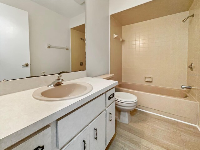 full bath featuring  shower combination, toilet, wood finished floors, and vanity