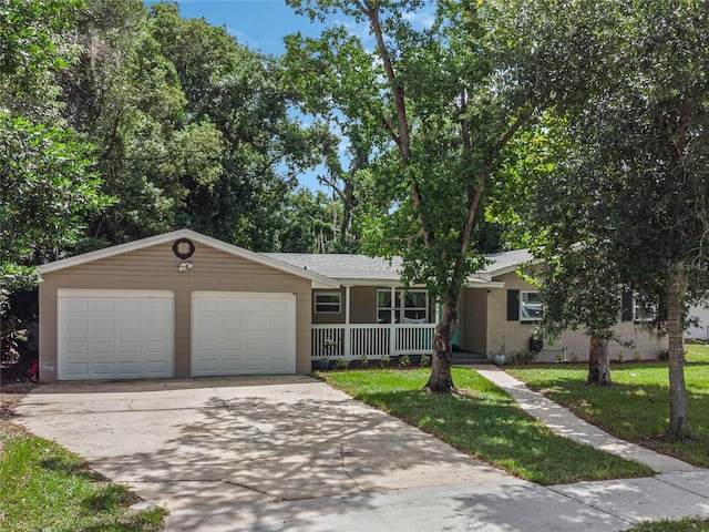 ranch-style home featuring covered porch, a garage, concrete block siding, driveway, and a front lawn