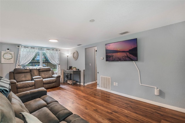 living room featuring baseboards, visible vents, and wood finished floors