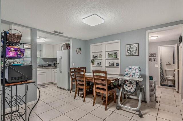 tiled dining room featuring a textured ceiling