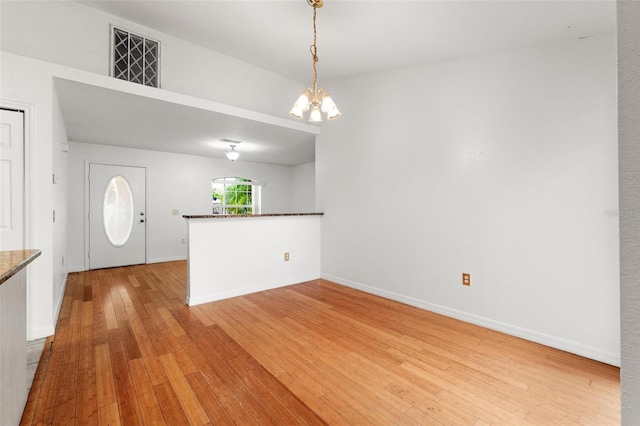 interior space featuring light wood-type flooring, kitchen peninsula, a notable chandelier, and pendant lighting