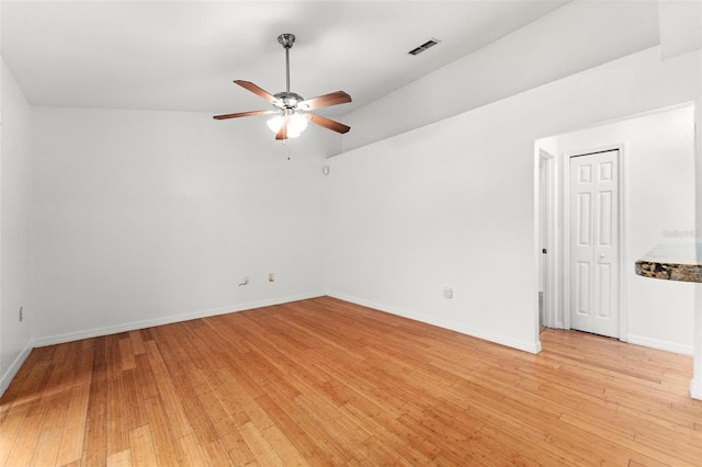 spare room with light hardwood / wood-style floors, vaulted ceiling, and ceiling fan