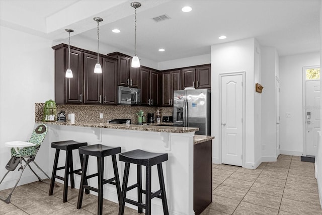 8110 Roseville Rd, Davenport, FL 33896 - kitchen with a breakfast bar, decorative backsplash, a peninsula, and stainless steel appliances