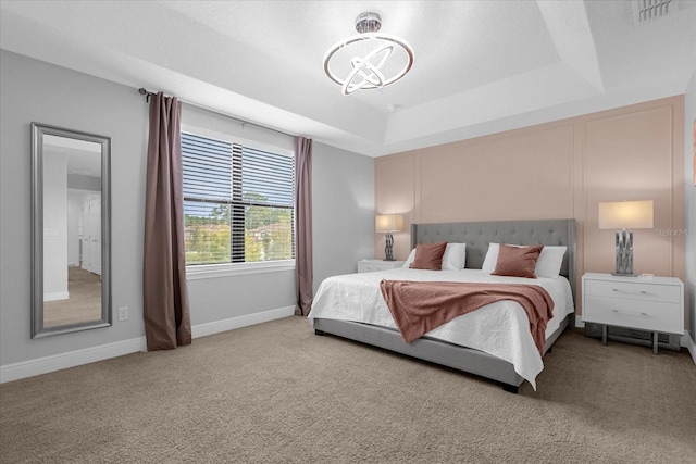 carpeted bedroom with a raised ceiling